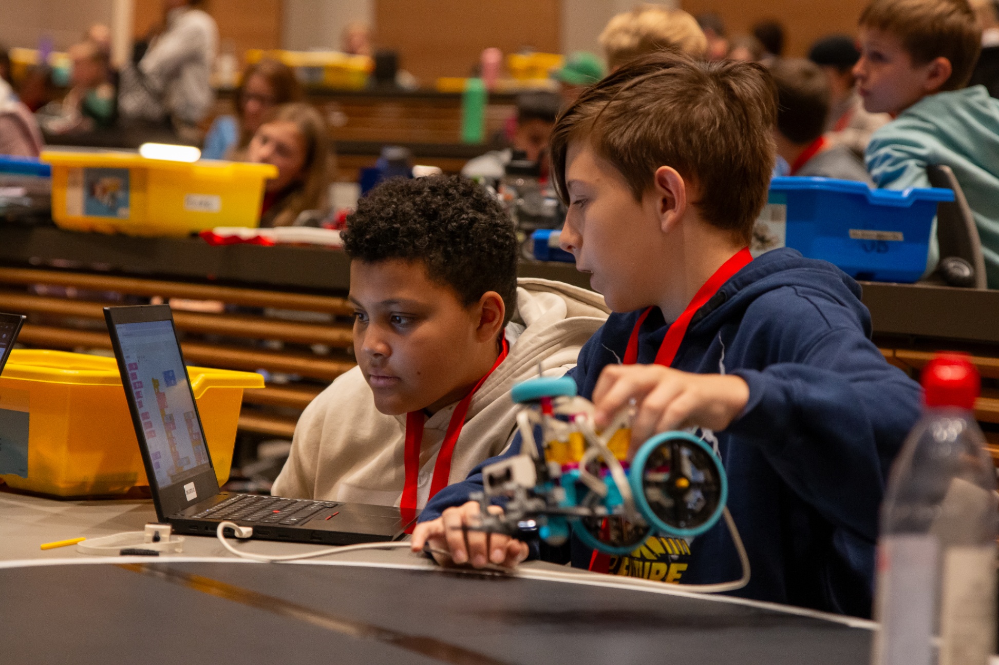 Two students at a laptop inspecting the code for their robot and making adjustments between rounds
