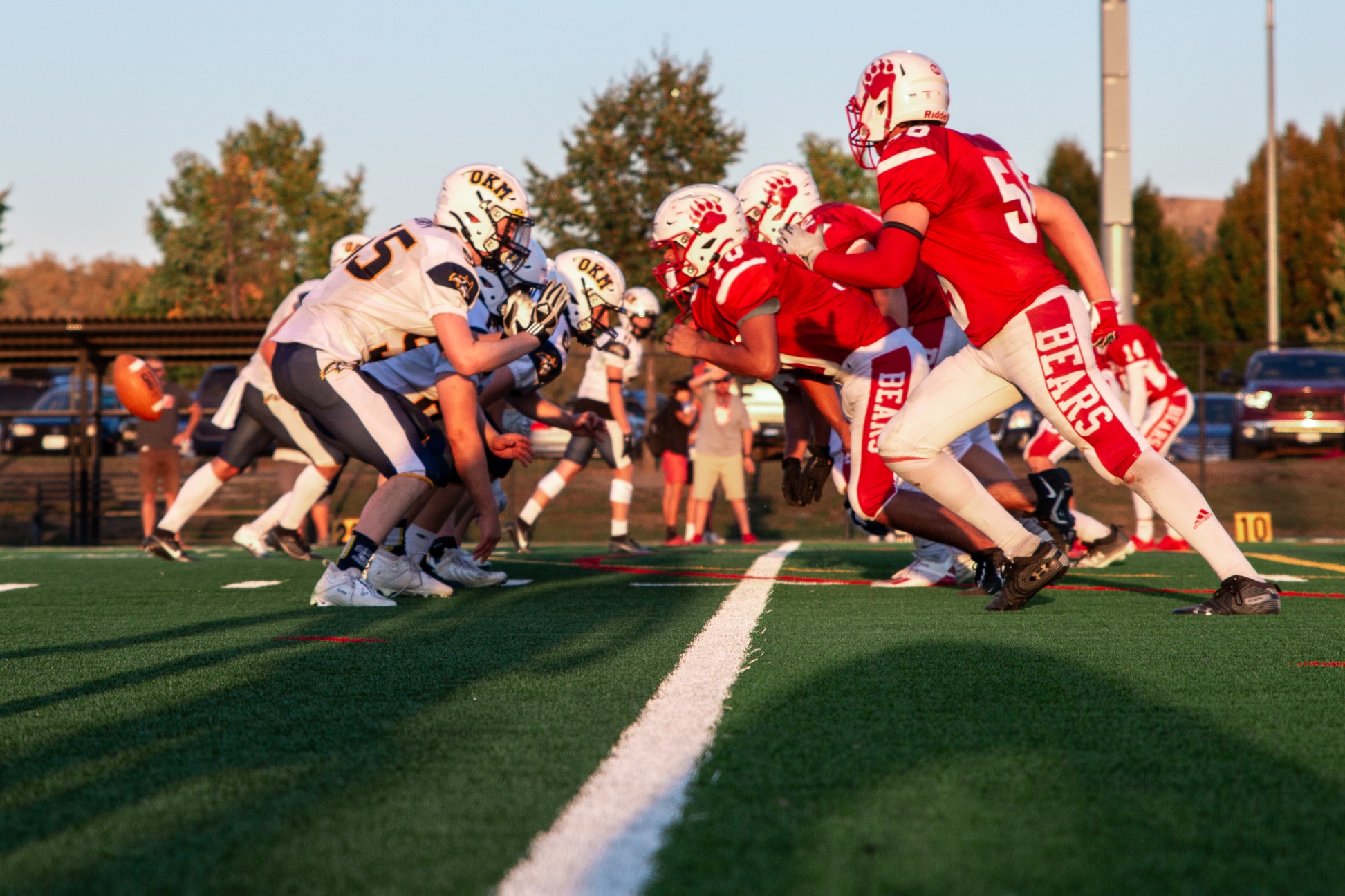 OKM and MBSS football players on the line of scrimmage as the ball is hiked